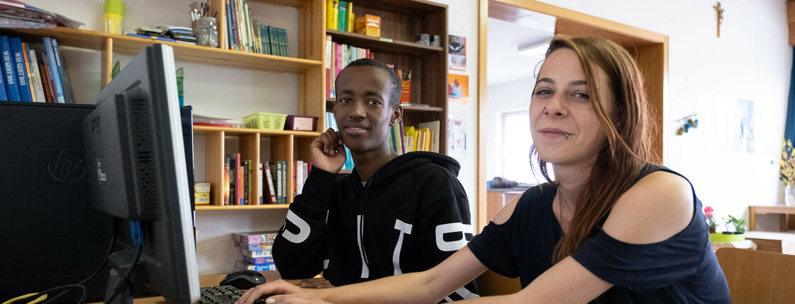 Ein Junge und eine Frau sitzen vor einem Computer