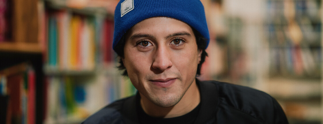 Portrait eines jungen Mannes mit schwarzem T-Shirt und blauer Mütze.