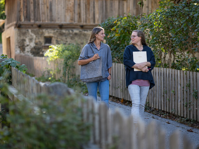 Zwei Haussammlerinnen gehen einen Fußweg in ihrer Gemeinde entlang und unterhalten sich.