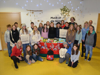 Viele Schüler*innen, vier Lehrer*innen und eine Caritas-Mitarbeiterin stehen zu einem Gruppenfoto zusammen.