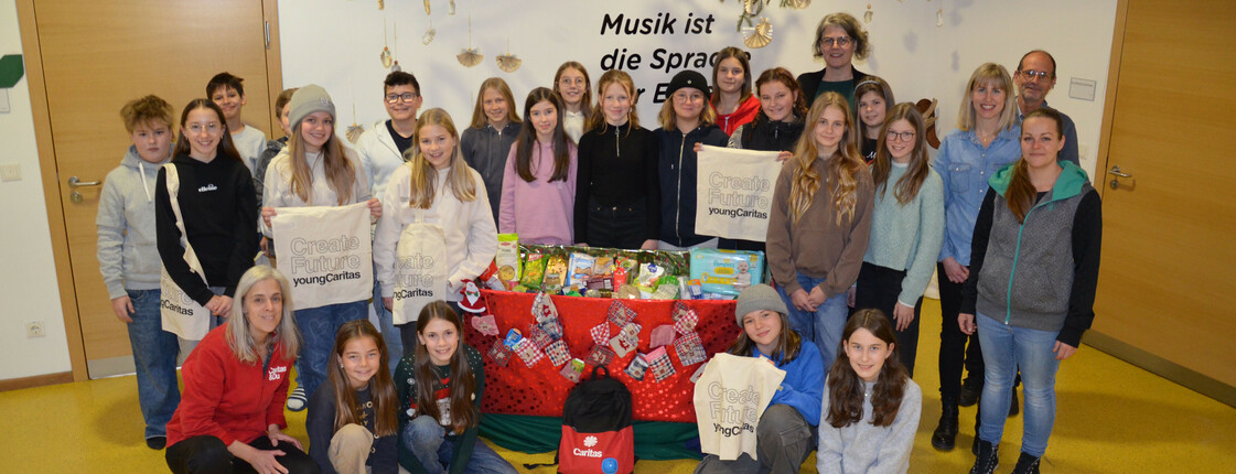 Viele Schüler*innen, vier Lehrer*innen und eine Caritas-Mitarbeiterin stehen zu einem Gruppenfoto zusammen.