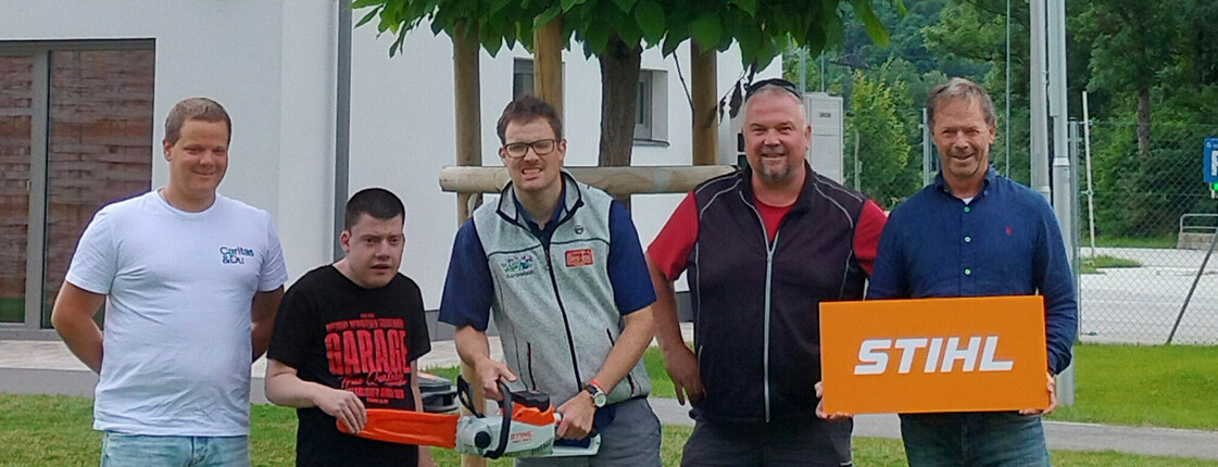 Fünf Personen stehen vor einem Gebäude zu einem Gruppenfoto zusammen.