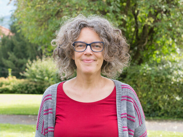 Portrait einer Frau mit rotem T-Shirt und Brille.