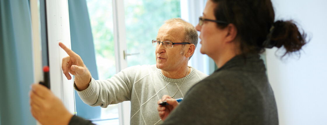 Bildungsreferent und Studentin am Whiteboard