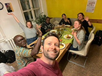 Selfie von sieben Personen, die an einem Tisch sitzen und zu Abend essen.