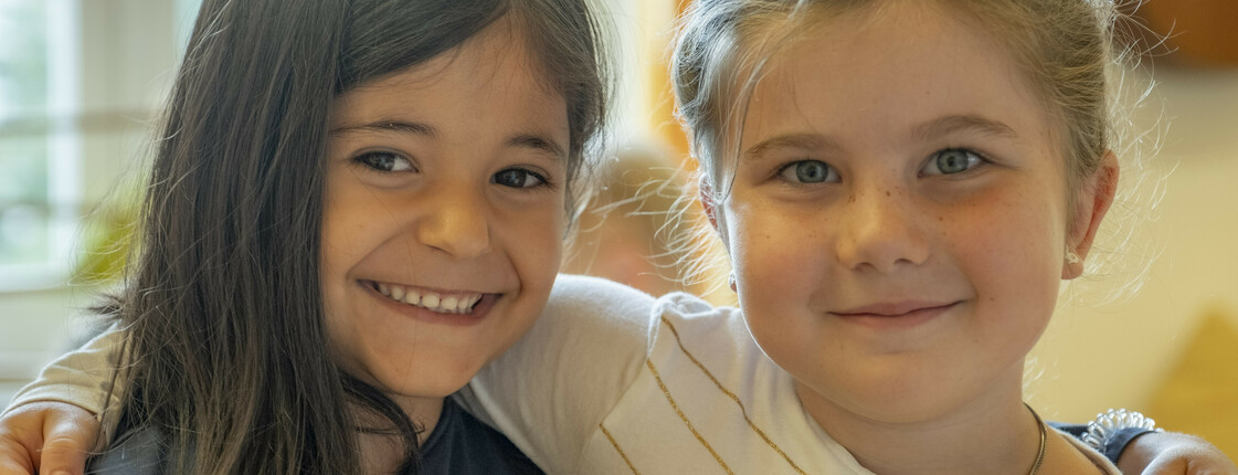 Zwei lachende Kindergarten-Freundinnen Arm in Arm