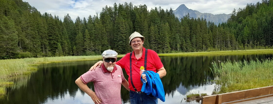 Zwei Männer stehen vor einem Bergsee zu einem Foto zusammen.