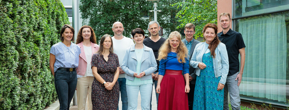 Zehn Personen stehen in einem Innenhof zu einem Gruppenfoto zusammen.