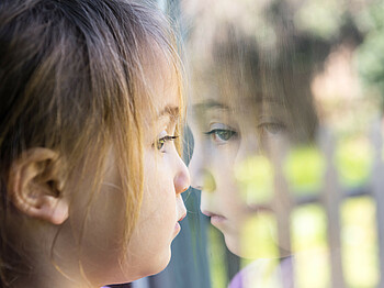 Serious girl looking through a window