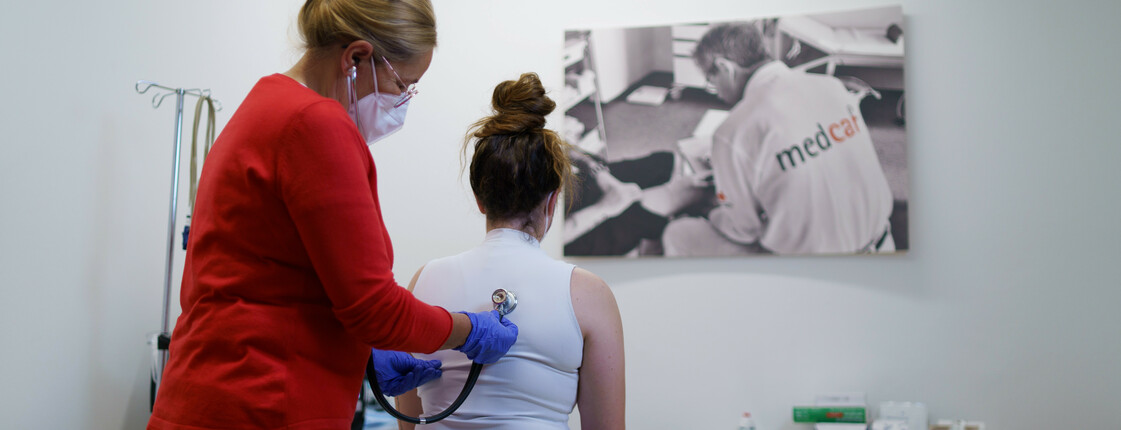 In einer Ordination hört die Ärztin eine Patientin mit dem Stethoskop ab.