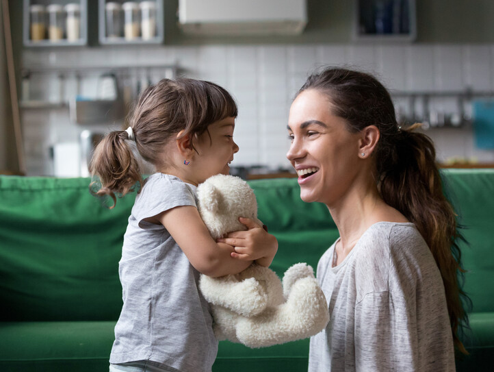 Smiling young mum talking with little daughter