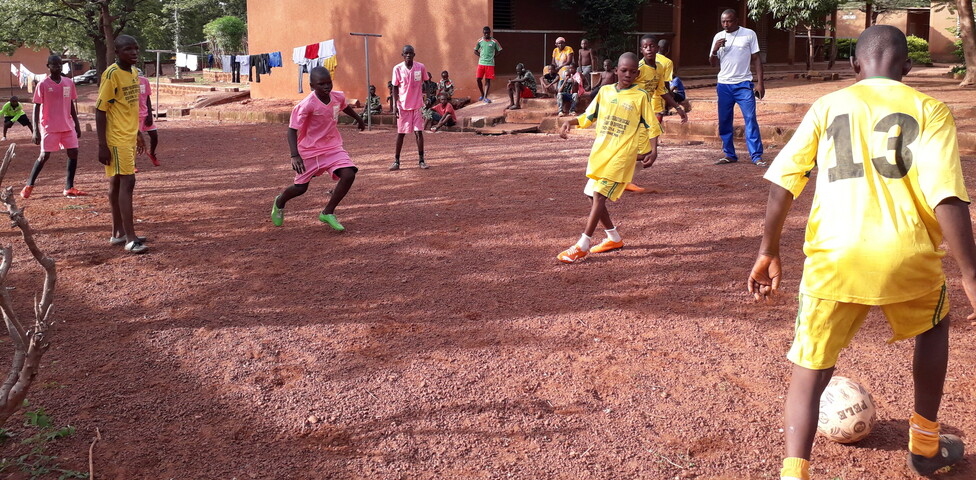 Kinder mit gelben und rosa Trickots spielen Fußball 