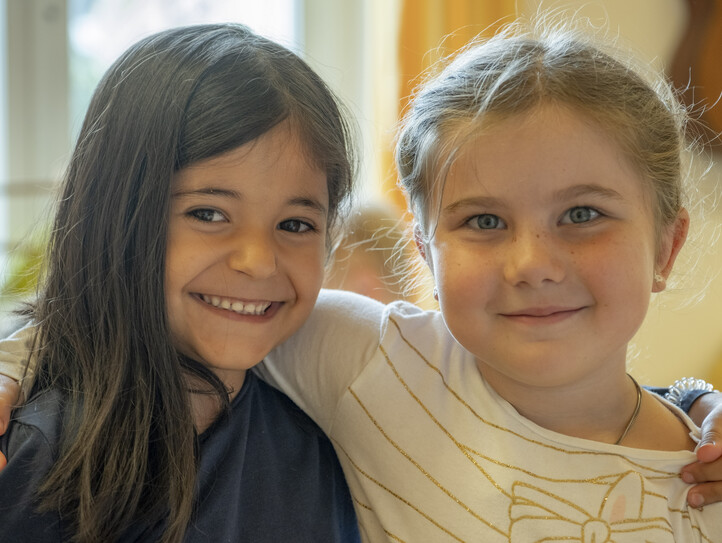 Zwei lachende Kindergarten-Freundinnen Arm in Arm